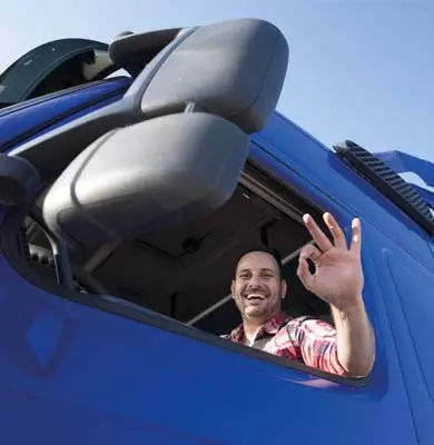 Ein Lkw-Fahrer grüßt zufrieden aus der Fahrerkabine seines Fahrzeugs